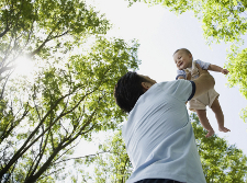 Mixed Race father holding baby in air