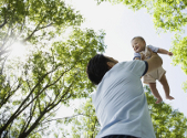 Mixed Race father holding baby in air