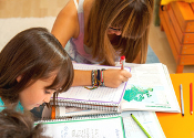 Three teenage girls busy with homework at desk.