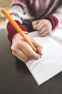 Child write in a notebook. Close up hand and pen