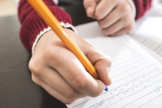 Child write in a notebook. Close up hand and pen