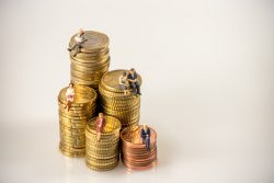 Various businesspeople sitting on money coin piles. Macro photo