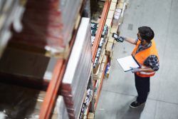 Worker with scanner making review of goods in warehouse